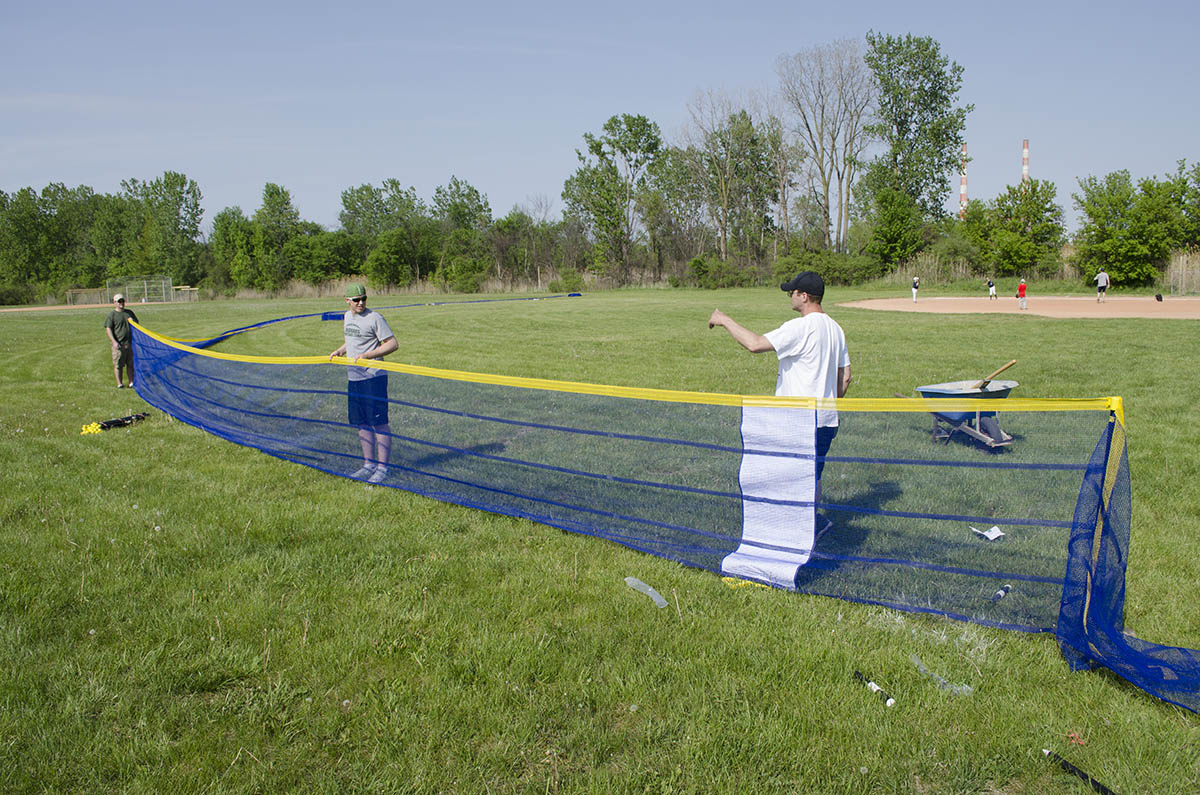 Volunteers install Grand Slam Fencing portable fence at Lions Park in Trenton, Michigan as the 10u Trenton Cubs practice. The blue fence will give the team a home run distance of 200 feet.